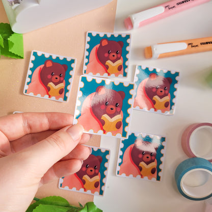 cute sticker of a bear wrapped in a blanket reading a book