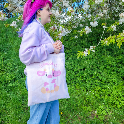 Light pink tote bag featuring an adorable pink cow design and the text okupoku