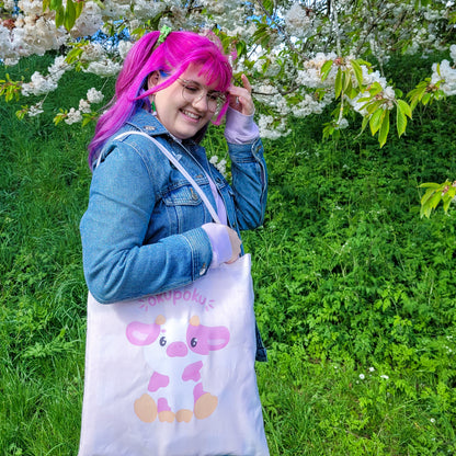 Light pink tote bag featuring an adorable pink cow design and the text okupoku