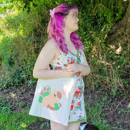 Natural colour tote bag featuring a cute capybara sitting with strawberries and a butterfly