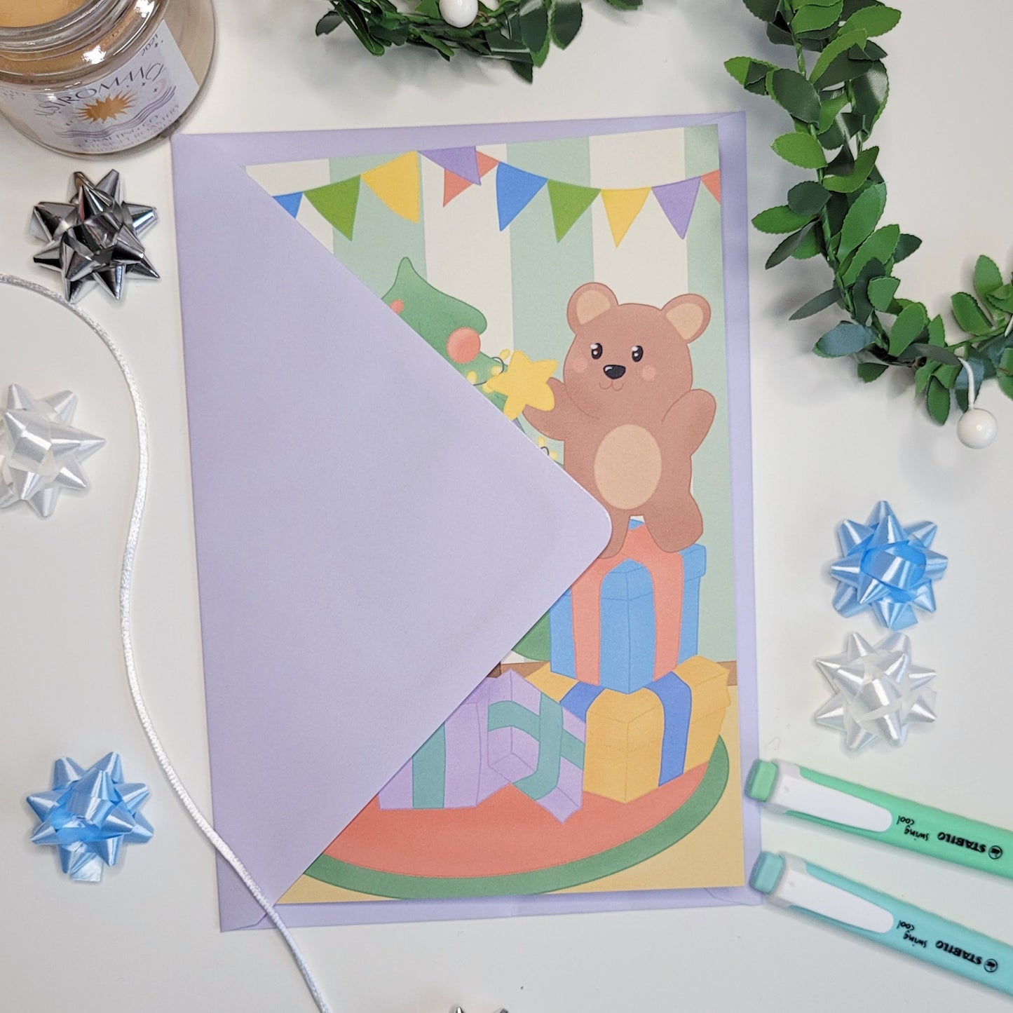 A cute christmas card featuring a little bear putting a star onto a christmas tree