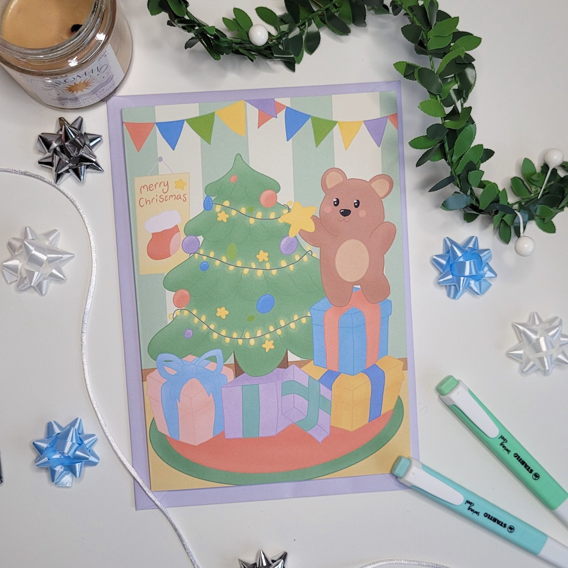 A cute christmas card featuring a little bear putting a star onto a christmas tree