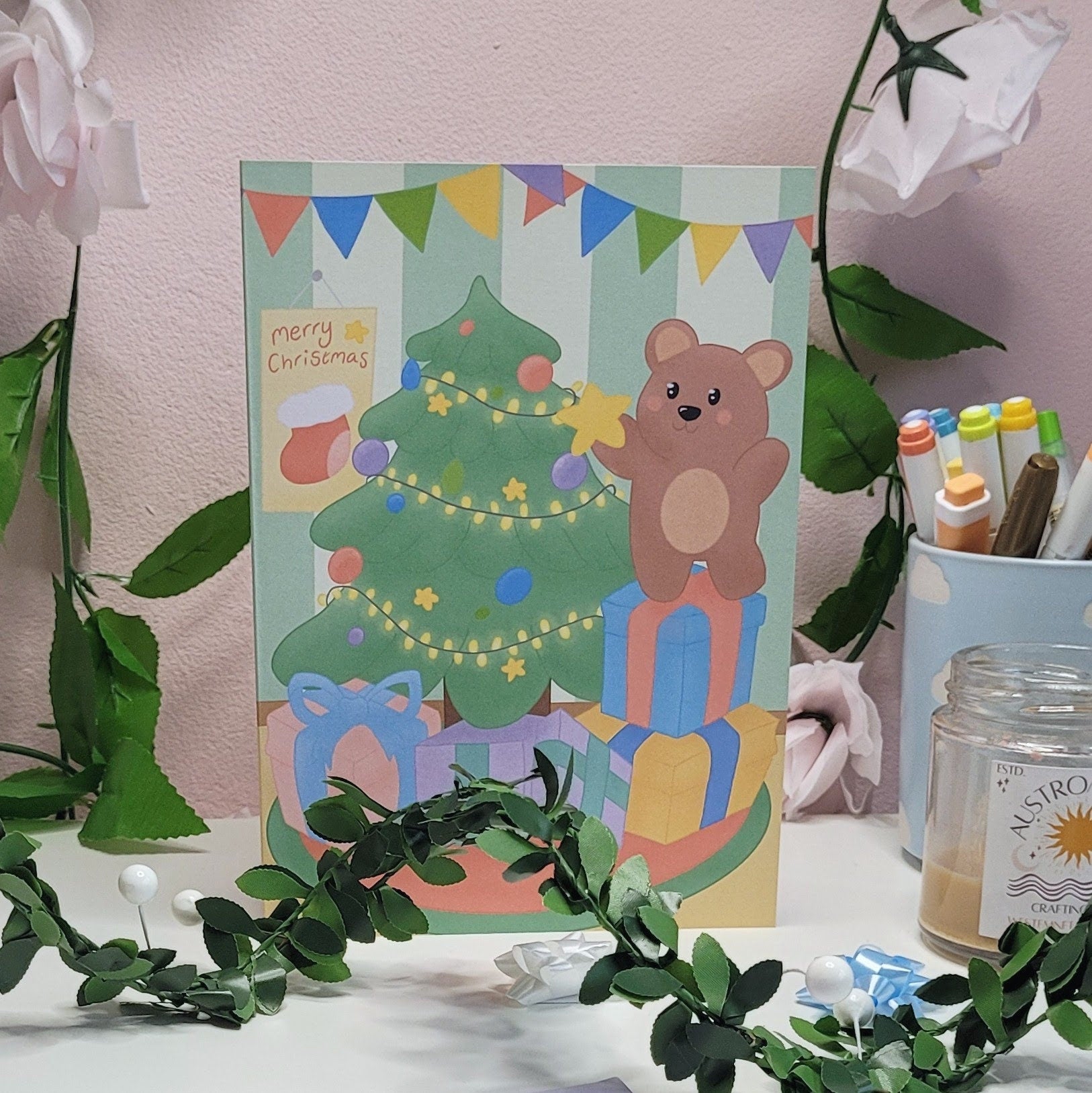 A cute christmas card featuring a little bear putting a star onto a christmas tree